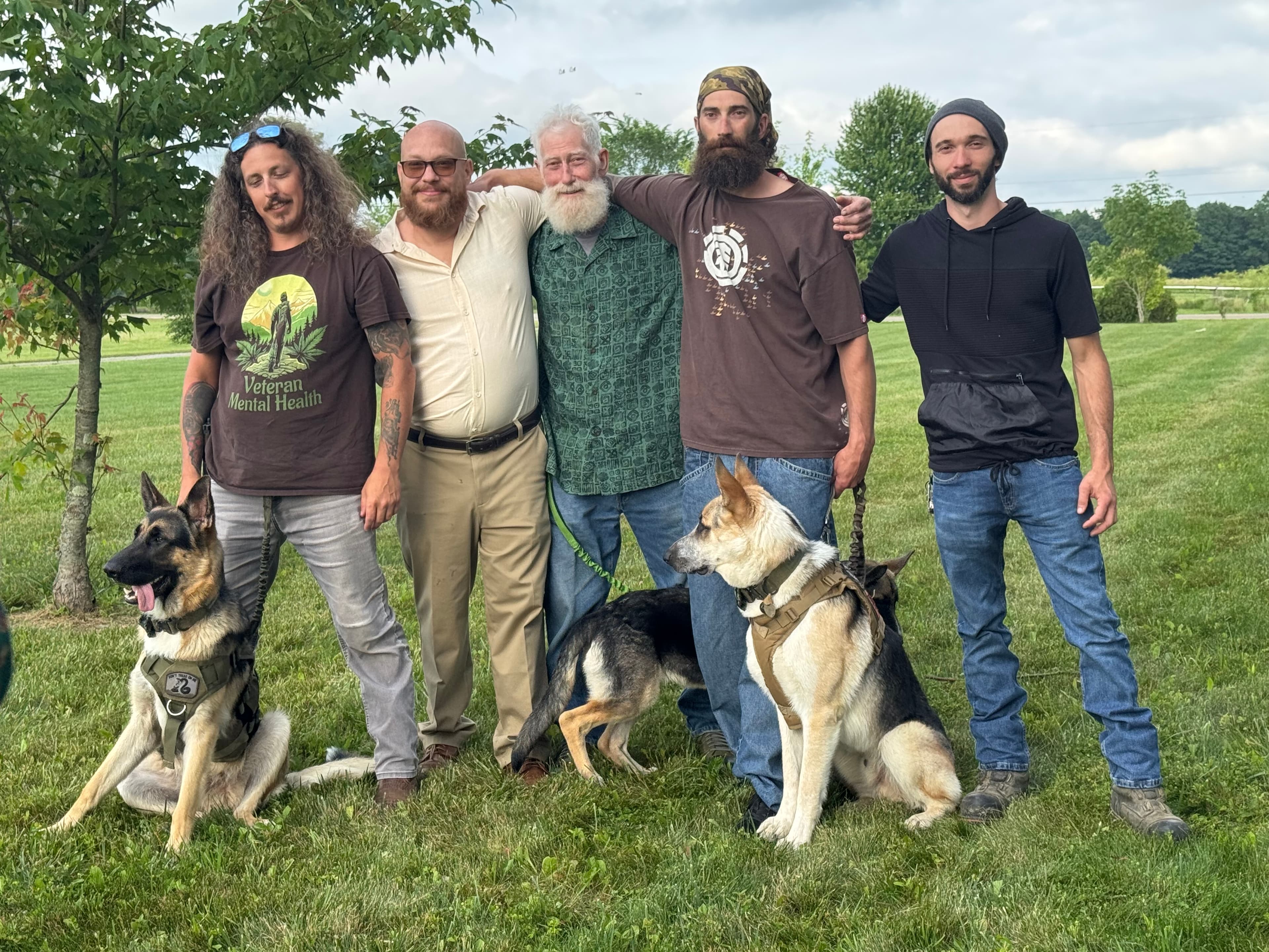 Patriot K9 community members and veterans gathered outdoors with German Shepherds.